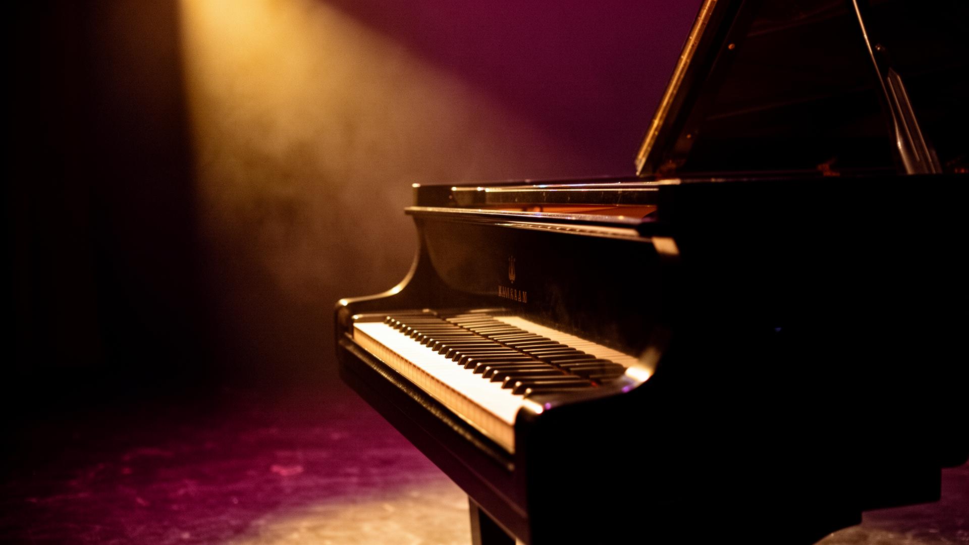 Grand piano illuminated by warm stage light